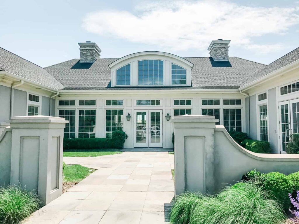The elegant exterior of Sparkling Pointe winery, featuring large windows, manicured shrubs, and a paved walkway leading to the main entrance.