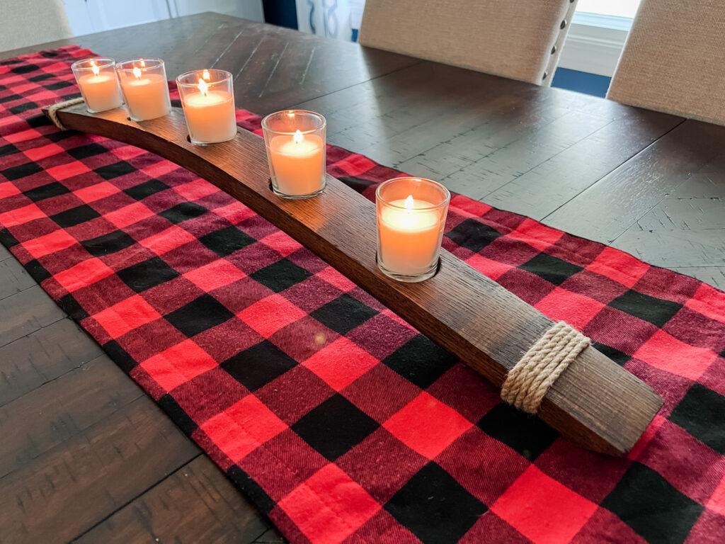 Wine stave centerpiece with lit candles on buffalo plaid table runner