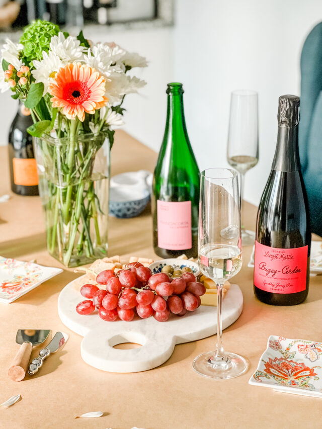 Bottles of sparkling wine on a table with flowers and grapes