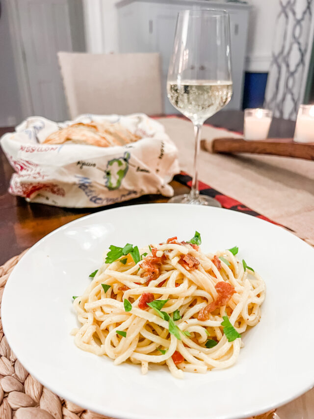 Pasta carbonara in a bowl with glass of white wine