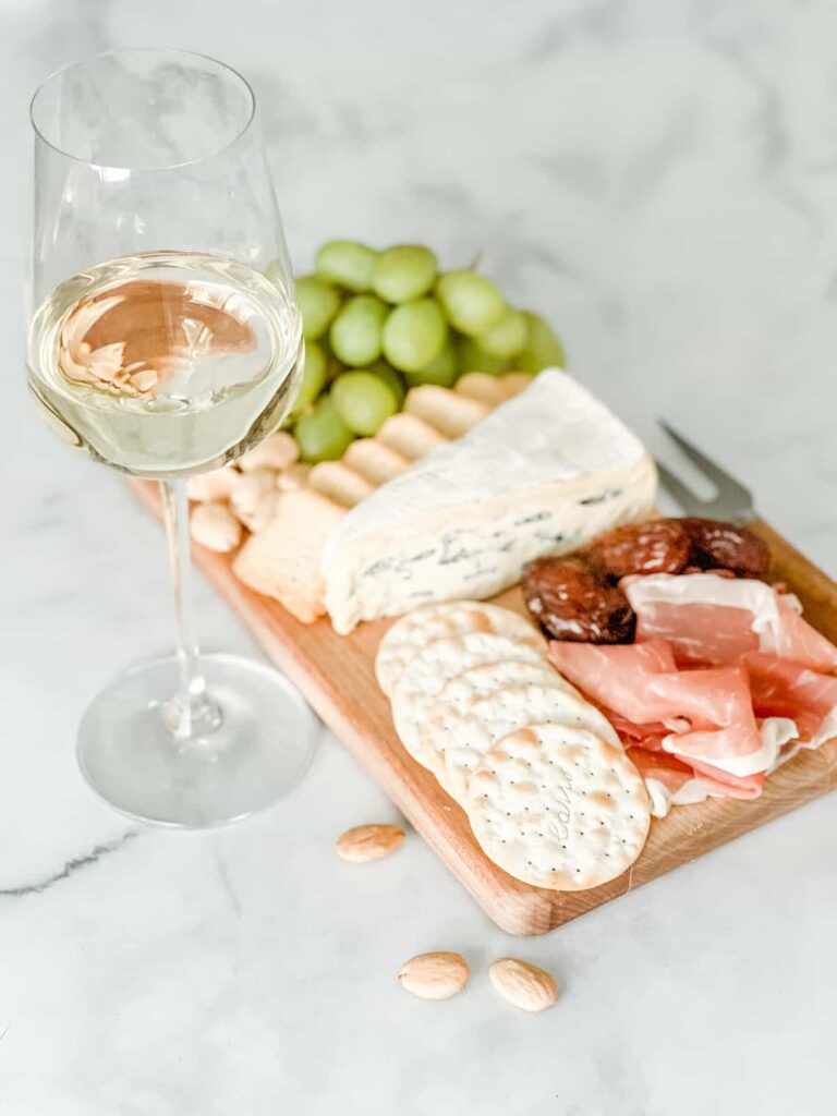 Cambozola and charcuterie board with glass of white wine