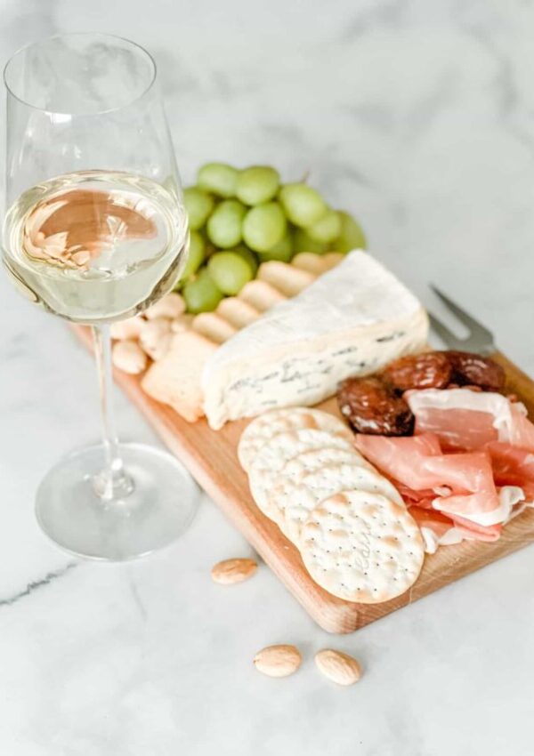 Cambozola and charcuterie board with glass of white wine
