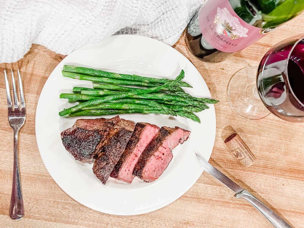 Filet mignon and asparagus with a bottle and glass of red wine