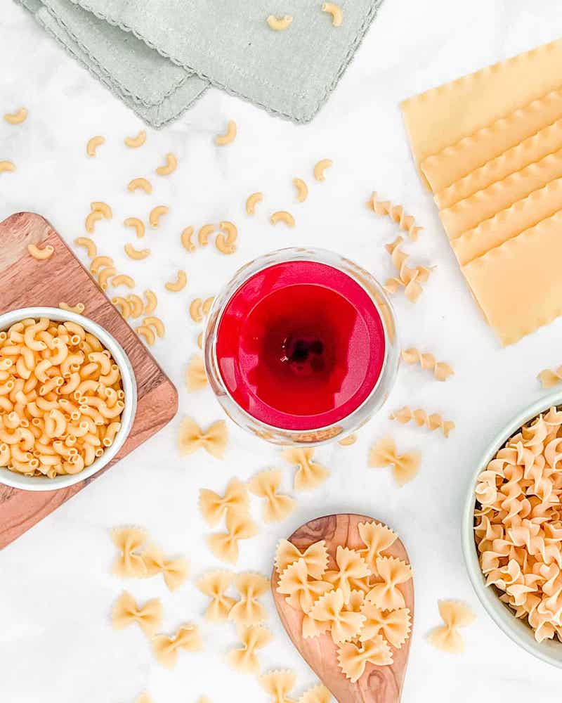 Glass of red wine with pasta in bowls