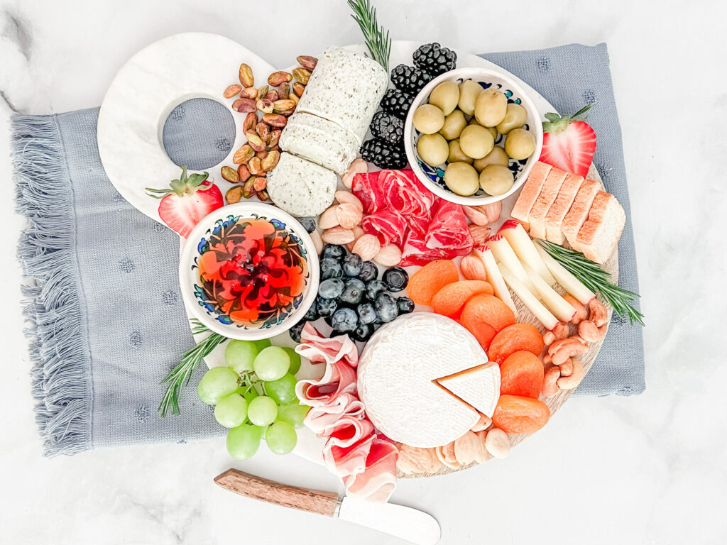 Gourmet snacks like cheese, charcuterie, and fruit on a charcuterie board