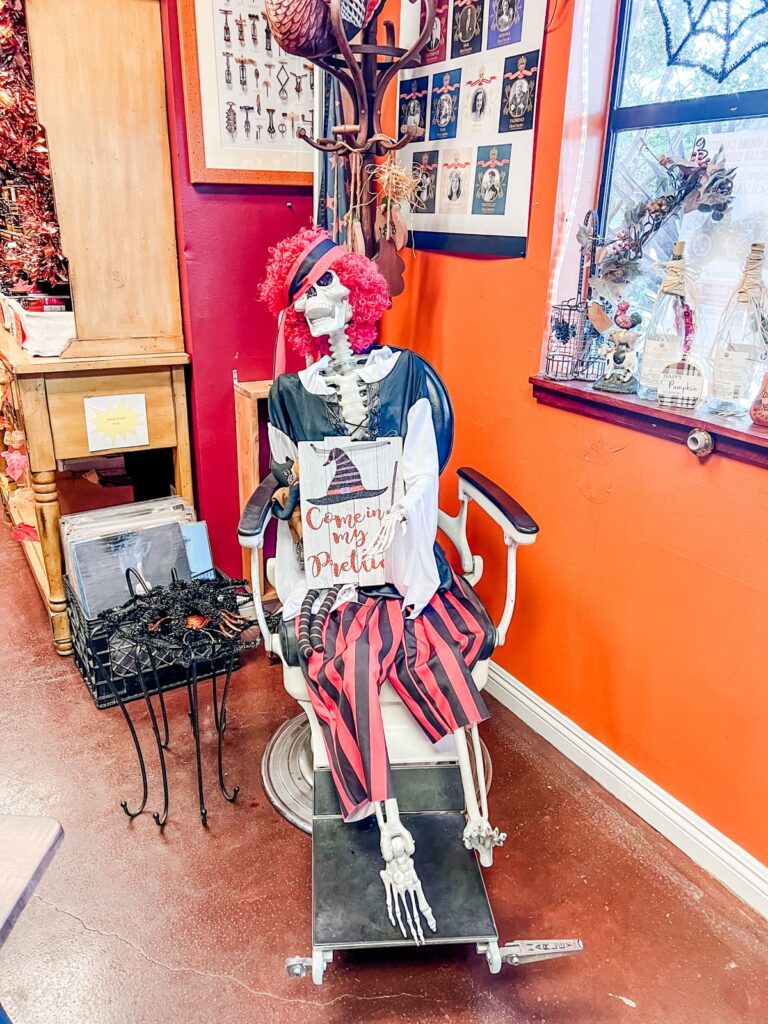 Whimsical Halloween decor in Casa Cassara's tasting room, featuring a skeleton with a red wig and festive attire, seated casually.