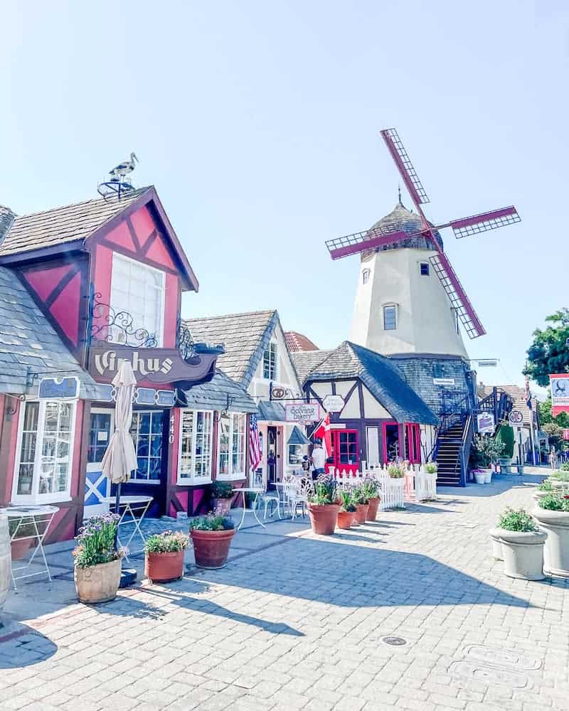 Charming street view in Downtown Solvang showcasing traditional Danish architecture with colorful buildings and a historic windmill under a clear blue sky