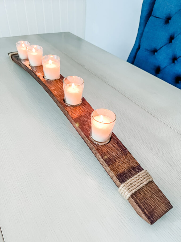 Side view of wine stave candle centerpiece on white table with blue bench in background