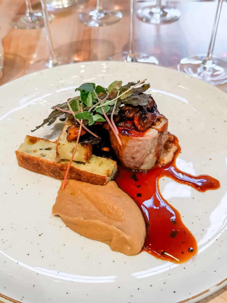 A beautifully plated dish at Au Pâturage featuring rabbit, mushrooms, onions, and garnished with microgreens.