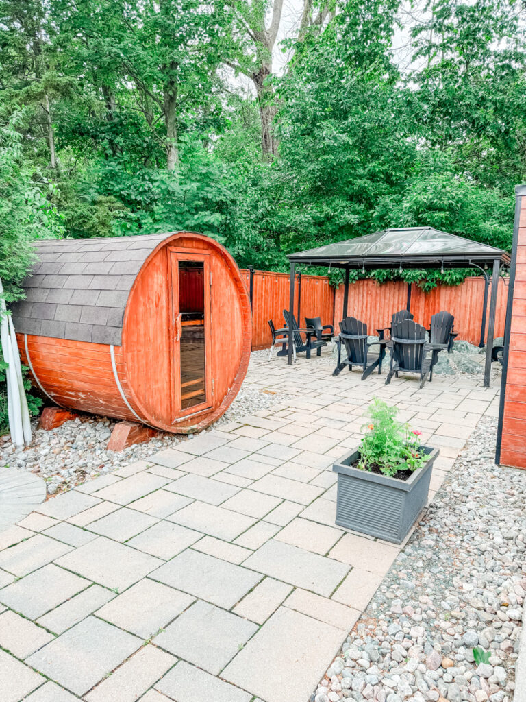 The outdoor thermal spa area at Hotel Montfort features a red cedar barrel sauna, lounge chairs under a gazebo, and a stone-paved terrace.