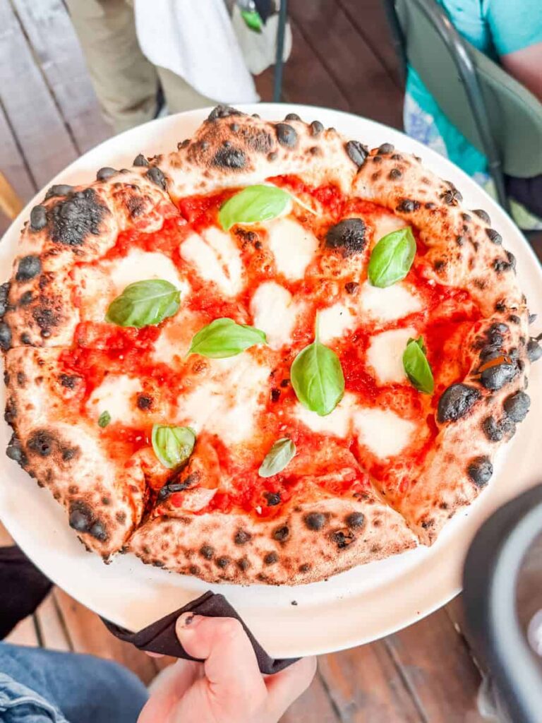 A freshly baked Margherita pizza served at Vignoble Ste-Pétronille’s on-site restaurant, topped with melted mozzarella, tomato sauce, and basil leaves.