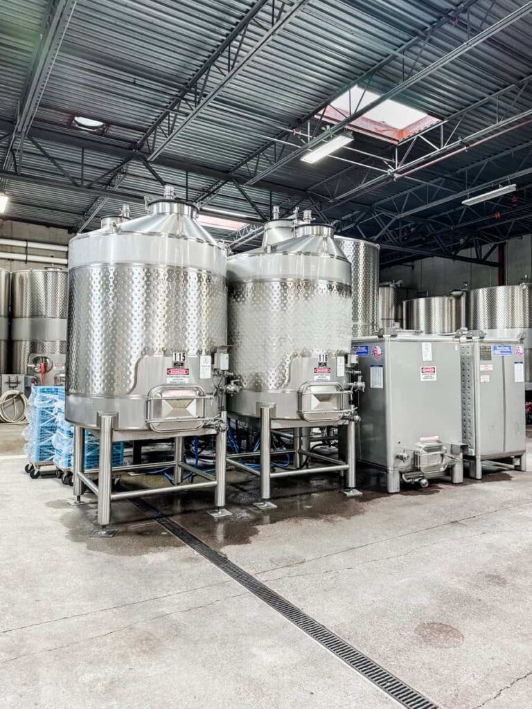 Stainless steel wine fermentation tanks at Ramey Cellars with overhead industrial lighting and a metal roof.
