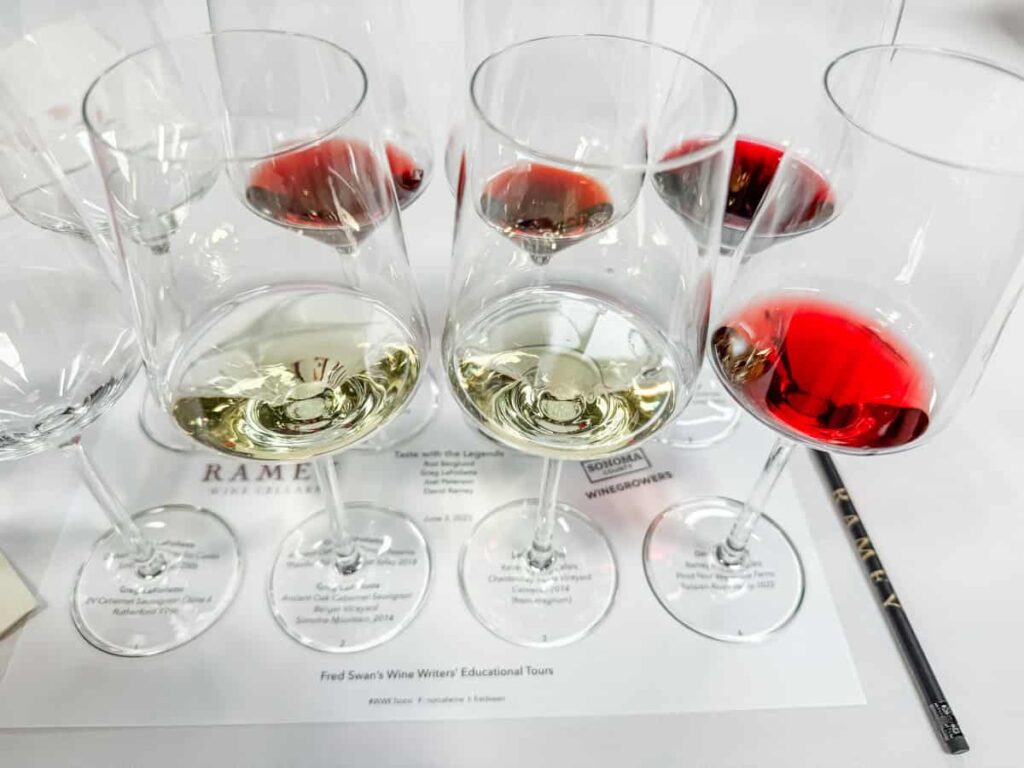 Elegant wine tasting glasses filled with white and red wines on a tasting sheet with the "RAMEY" logo.