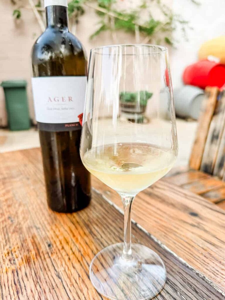 Glass of white wine next to a bottle of Ager from Braća Plančić, part of a tasting experience at this Hvar winery.
