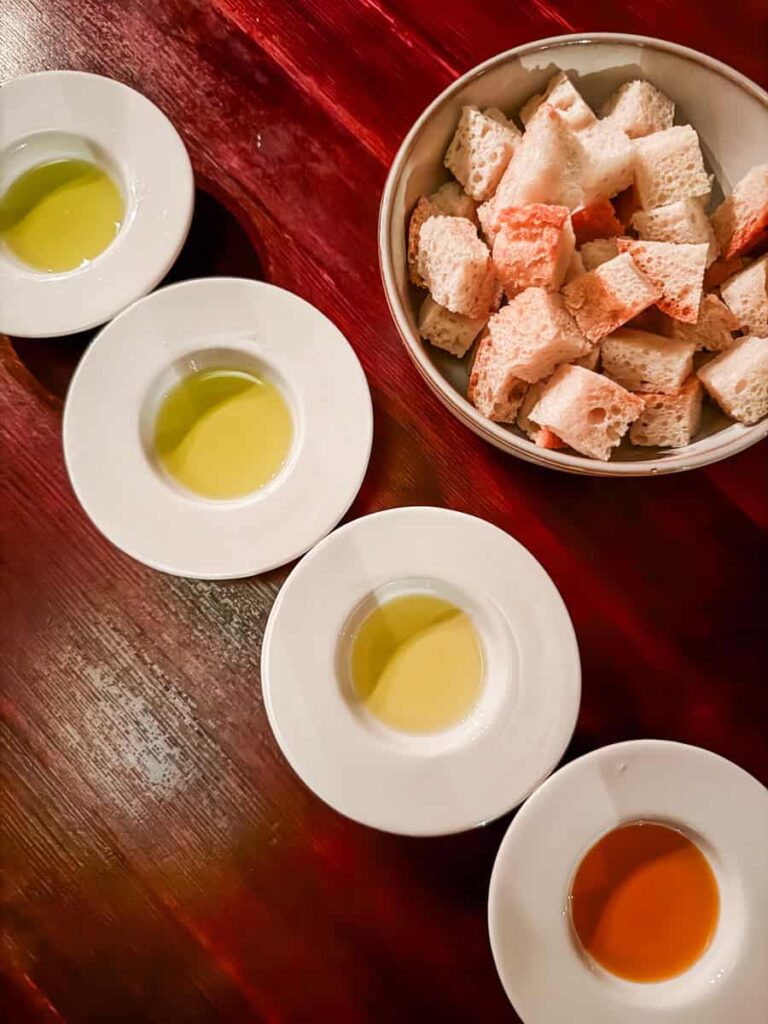 Tasting setup at Duboković Wines on Hvar Island with four samples of olive oil and a bowl of rustic bread.