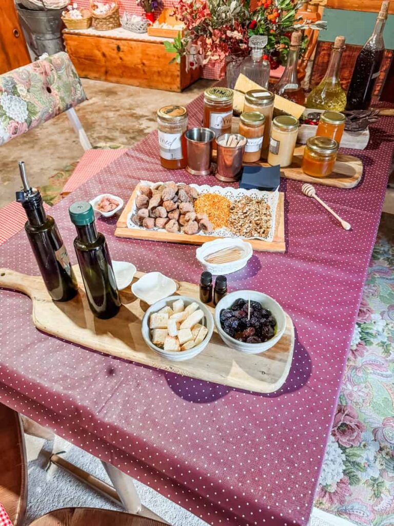 Mikletovi honey tasting setup featuring honey jars, olive oil, dried figs, cheese, and nuts.