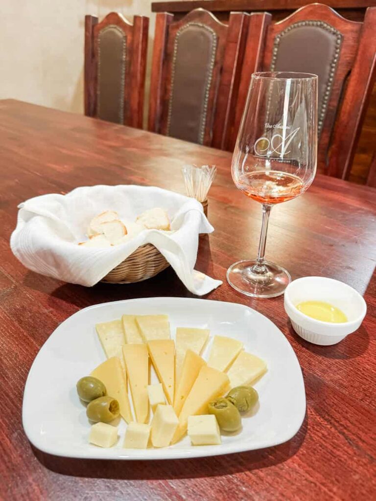 Wine tasting at Antičević winery with local cheeses, olives, bread, olive oil, and a glass of rosé.