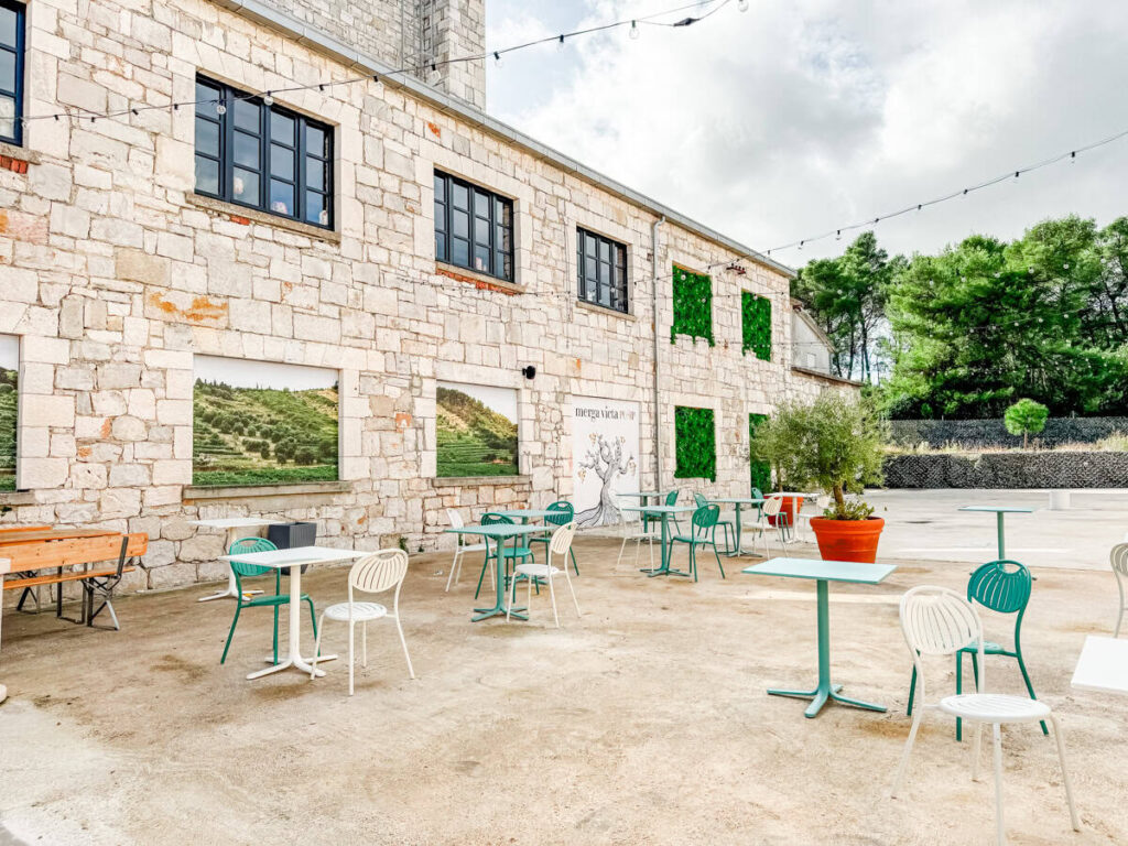 Outdoor patio seating at Merga Victa Winery with stone façade and green accents on Korčula Island.