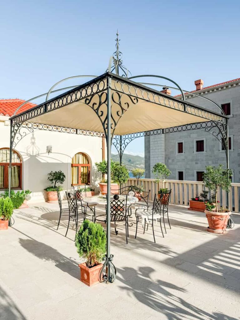 Terrace at Korta Katarina with wrought-iron gazebo and seating area near the coast.