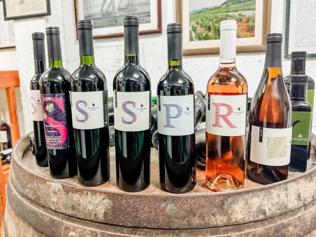 Bottles of Miloš Winery wines displayed on a wooden barrel in the tasting room.