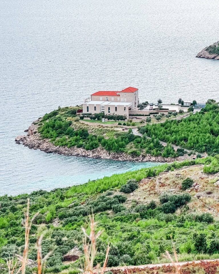 Modern winery building with red roof on a rocky point by the sea surrounded by vineyards on the Pelješac Peninsula.