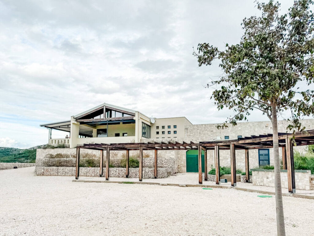 Terra Madre winery exterior with modern stone building and pergola walkway.