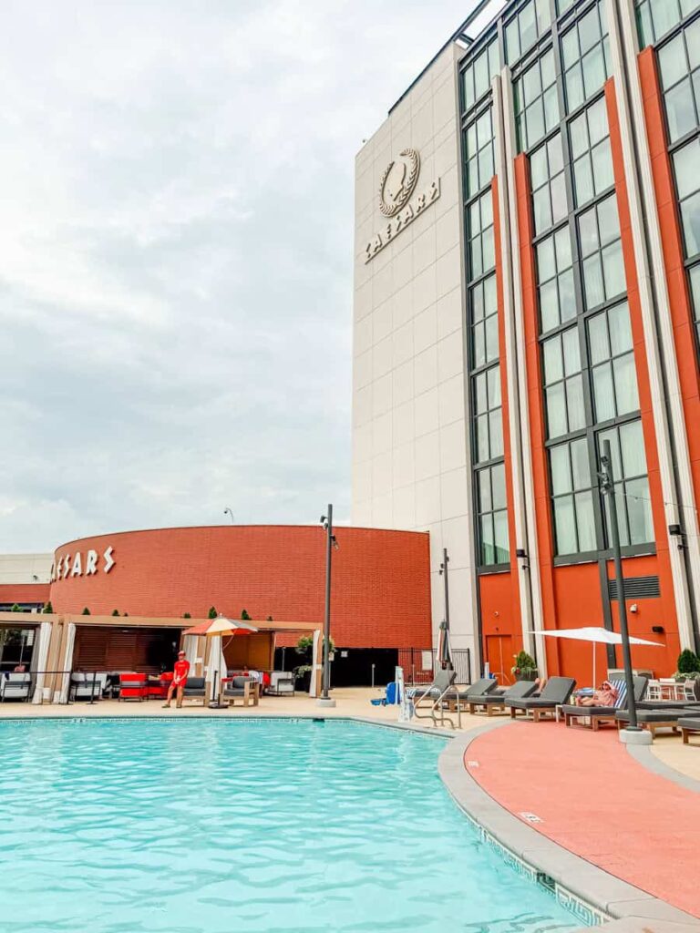 Outdoor pool at Caesars Virginia with lounge chairs, cabanas, and the hotel tower overlooking the pool deck.