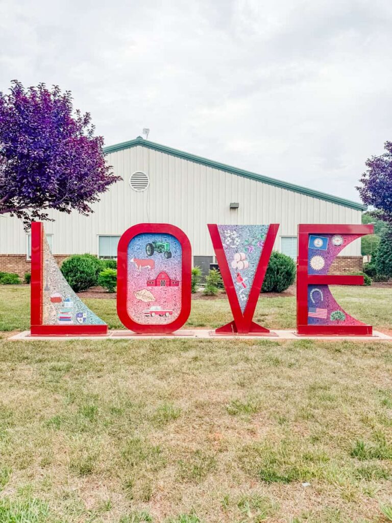 Bright red LOVE sign in Chatham with colorful illustrations inside each letter celebrating local agriculture, history, and community.