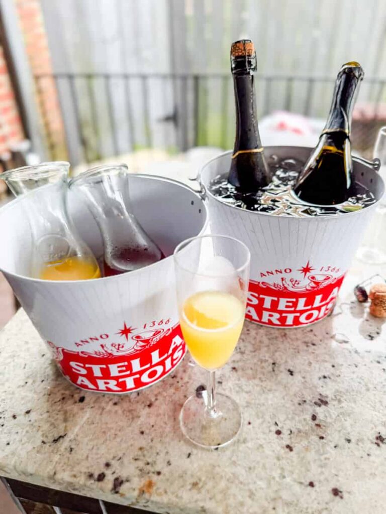 Mimosa flight with carafes of fruit juices, sparkling wine on ice, and a filled champagne flute at Crema & Vine.