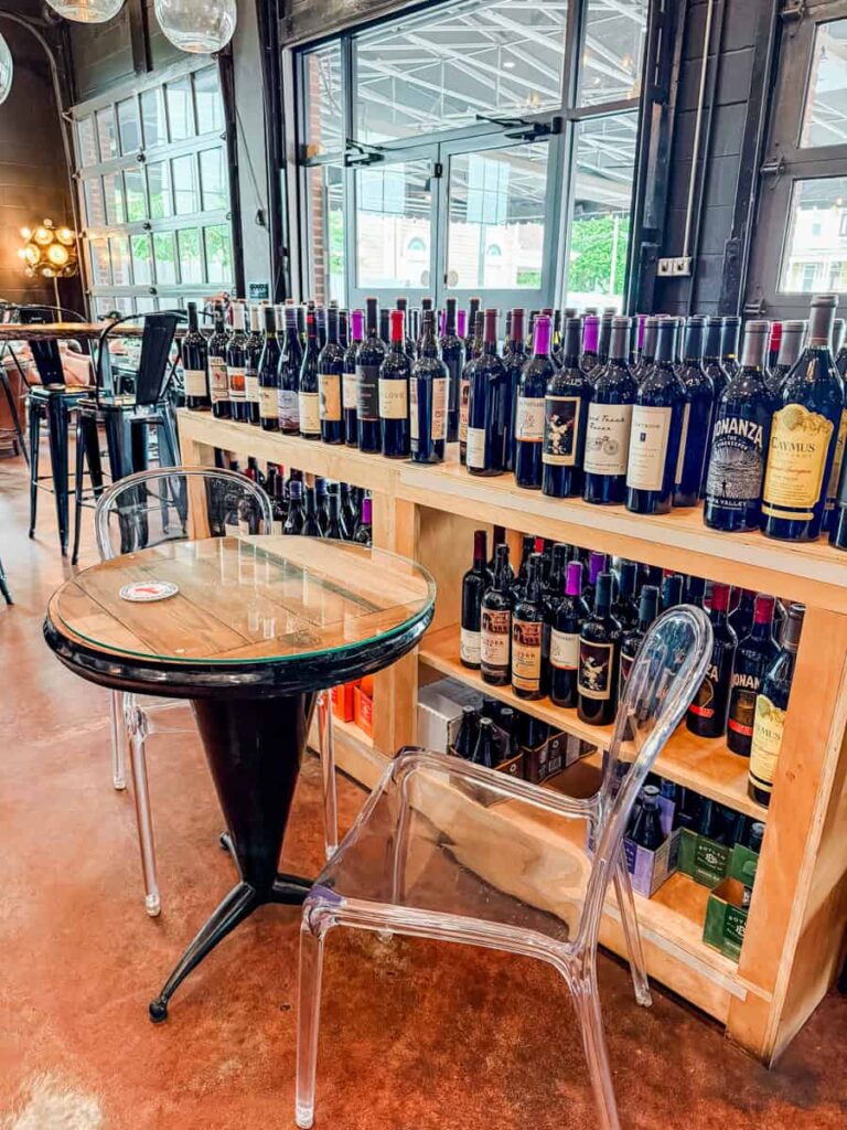 Shelves stocked with bottles of red wine beside café seating inside Crema & Vine.