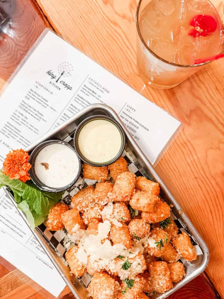 Crispy truffle tater tots topped with grated Parmesan and herbs served with two dipping sauces at King Cropp Kitchen.