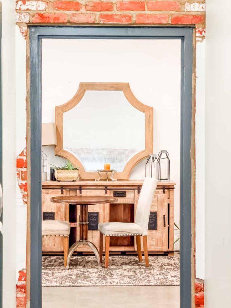 Cozy seating area inside Links Coffee House Cafe with a wooden table, upholstered chairs, a large decorative mirror, and exposed brick accents.
