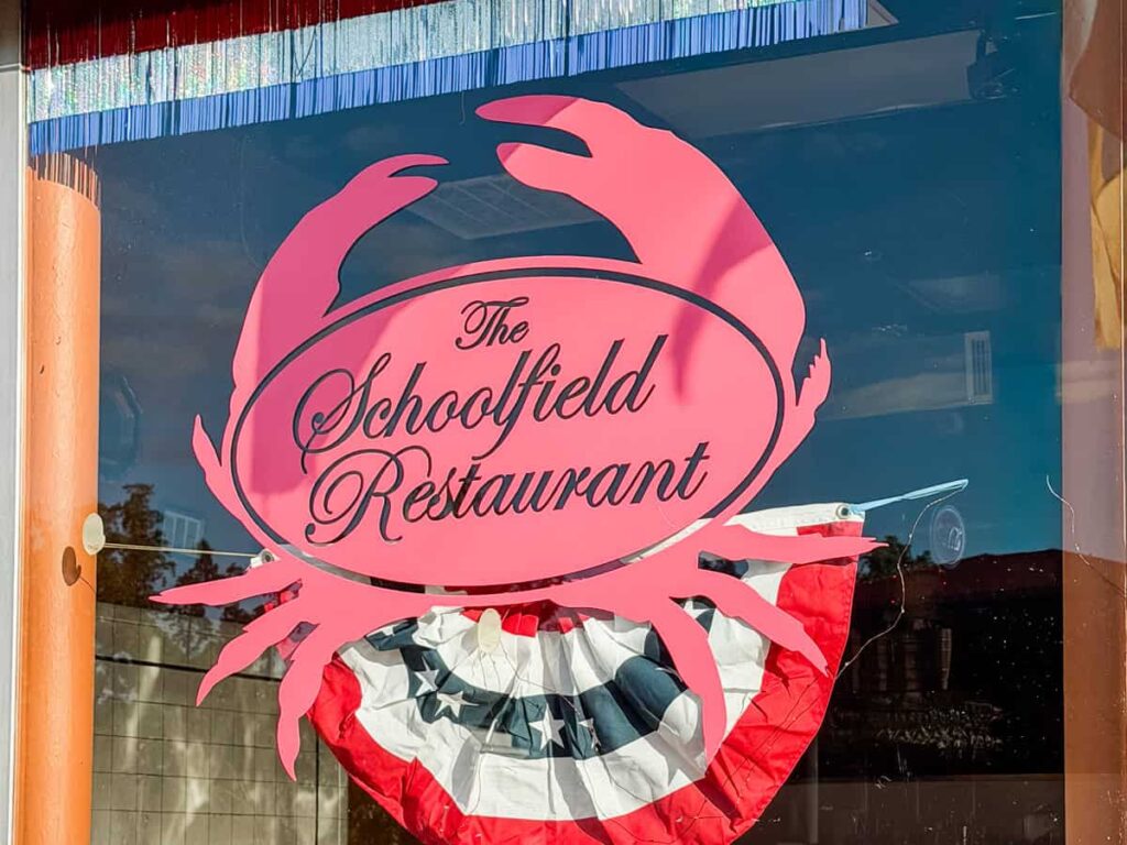 Front window of The Schoolfield Restaurant with a large red crab logo and the words "The Schoolfield Restaurant".