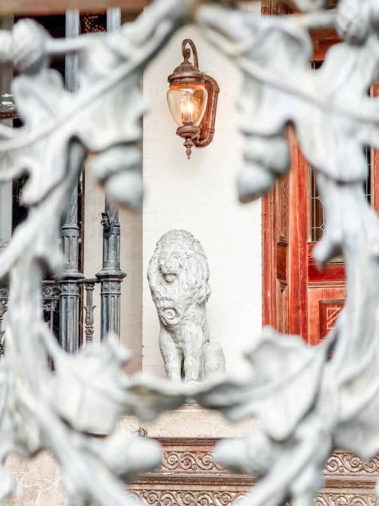 Stone lion statue on the front porch of a historic home framed by an ornate wrought iron fence in Danville's Old West End.