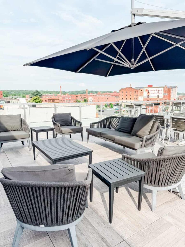 Rooftop lounge at The Bee with cushioned seating, large umbrellas, and views overlooking downtown Danville.
