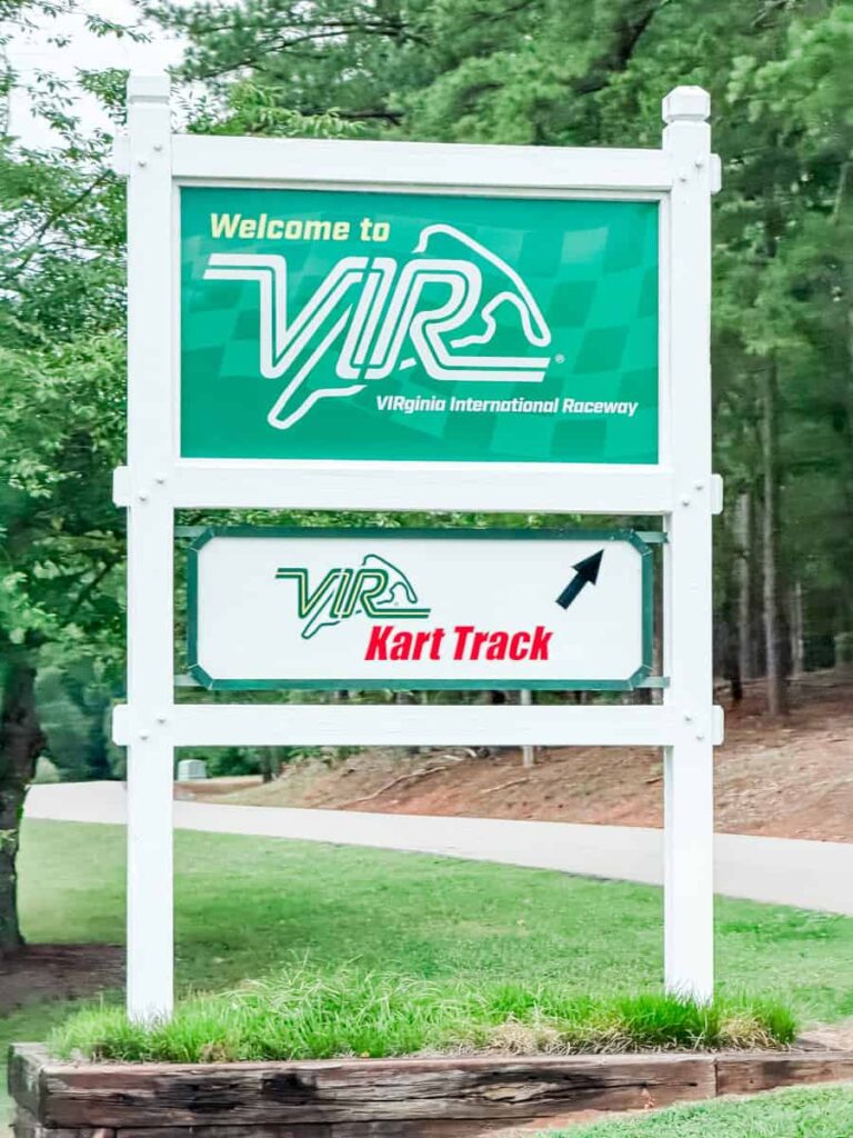 Entrance sign for Virginia International Raceway with directions to the kart track surrounded by trees and landscaped grounds. Text reads "Welcome to VIR Virginia International Raceway" and "VIR Kart Track."